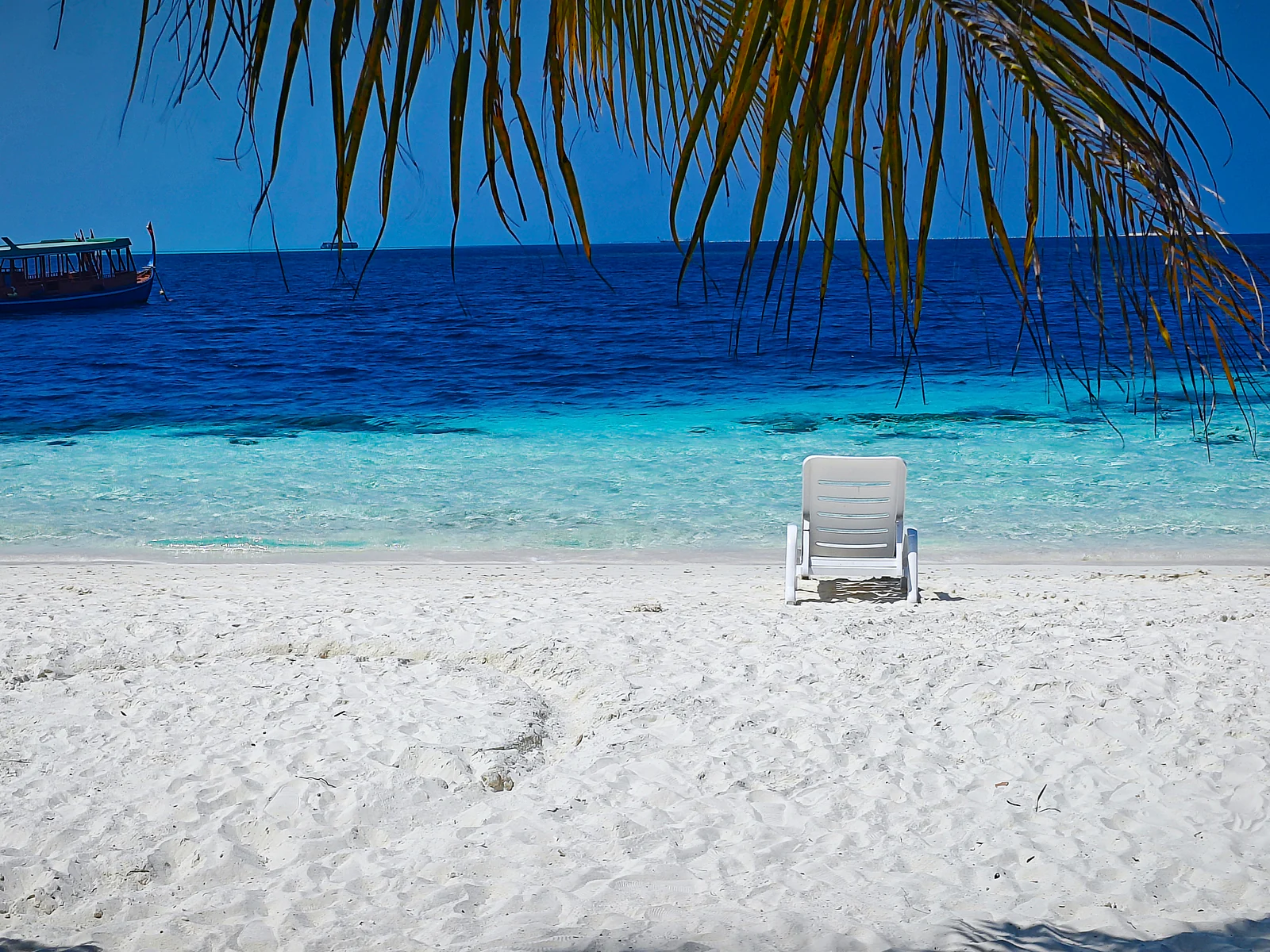 Ruhiger Liegestuhl am weißen Strand mit blauem Meer auf den Malediven